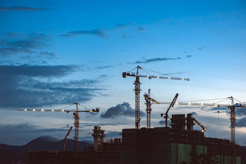 Increases in the supply of buildable land by expanding growth boundaries (numerous construction cranes at dusk)