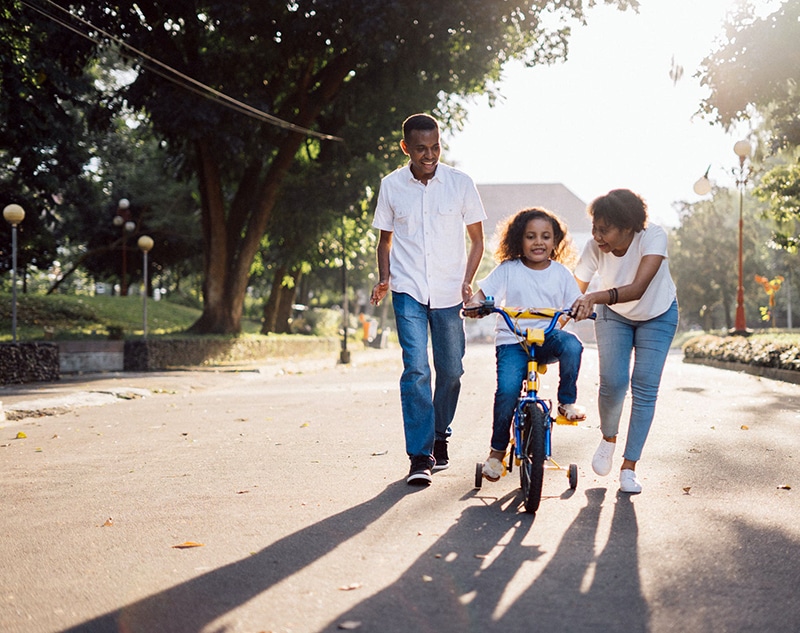Allocating resources to address housing needs among various household types, including older adults and families with children (parents helping daughter ride bike)