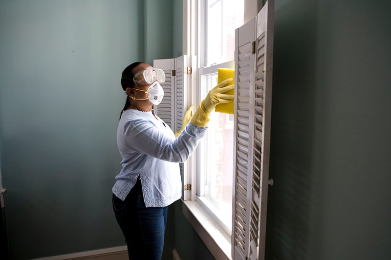 Health and housing (woman in protective gear washing windows)