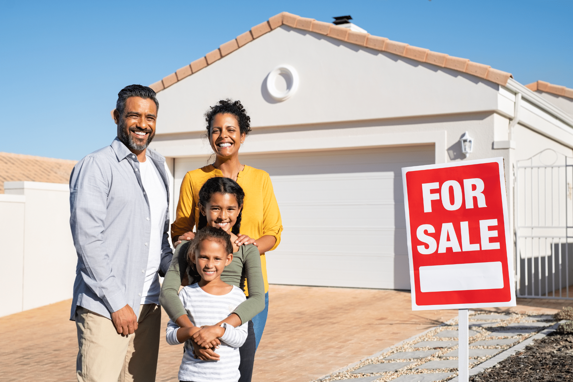 Mixed race family standing in front of a new home they have purchased is used to illustrate recent trends in households of color home ownership