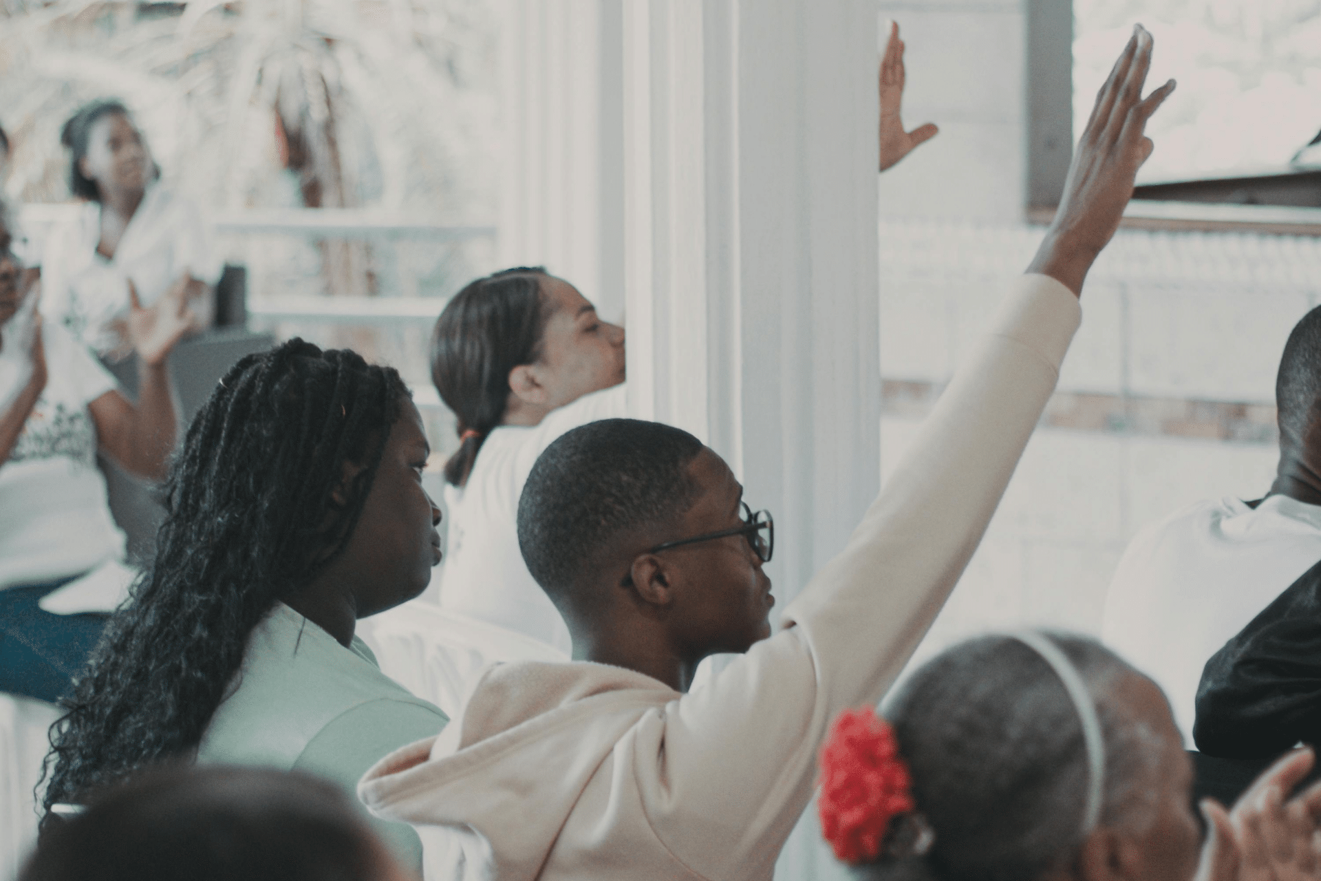 Image of a man raising his hand at a community meeting used to illustrate community engagement